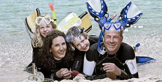 perhe rannalla snorklaamassa